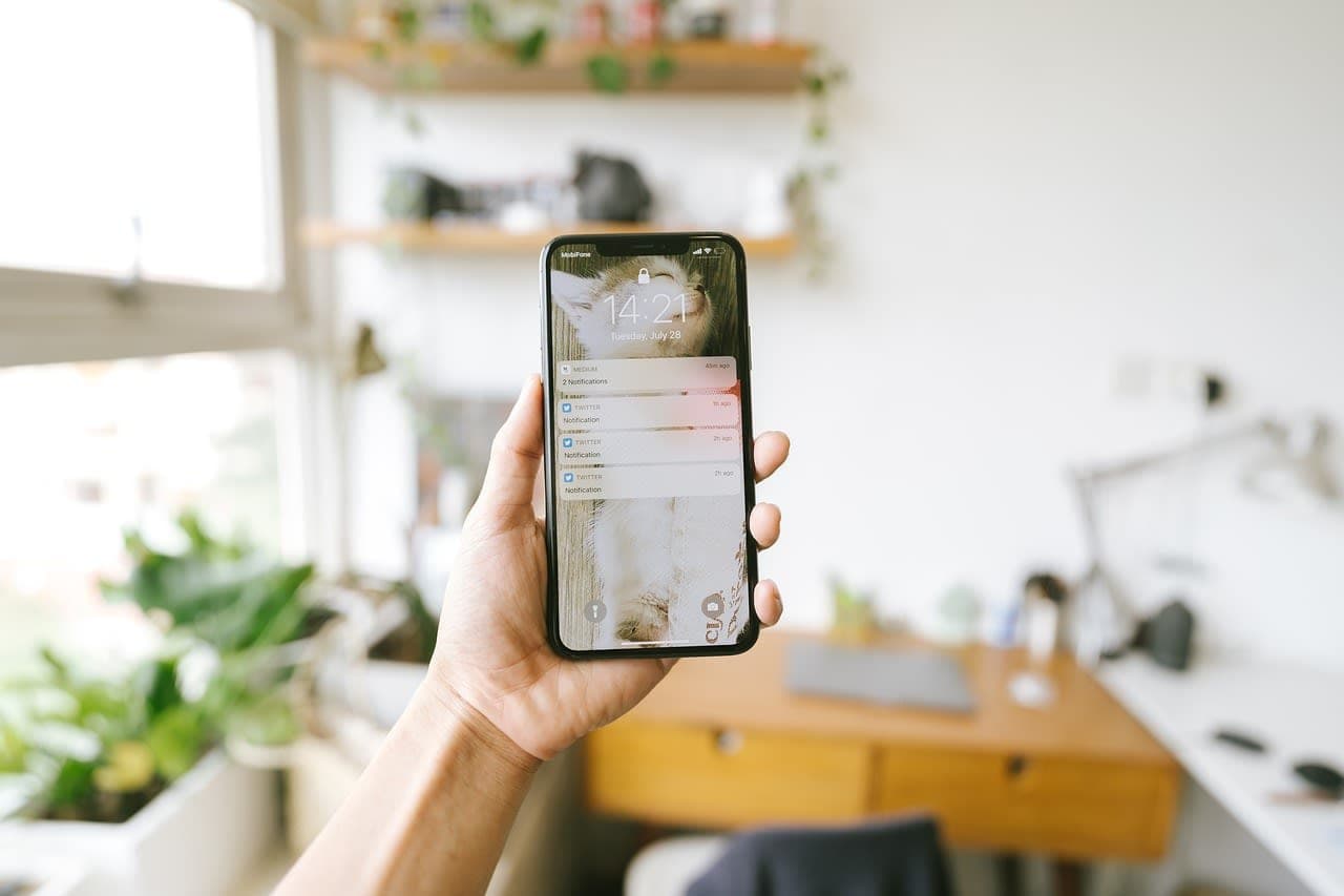 Zwei-Faktor-Authentifizierung und eine Pruefung der App-Berechtigungen sind die erste Verteidigungslinie. smartphone on wooden desk showing lock screen, soft daylight from window