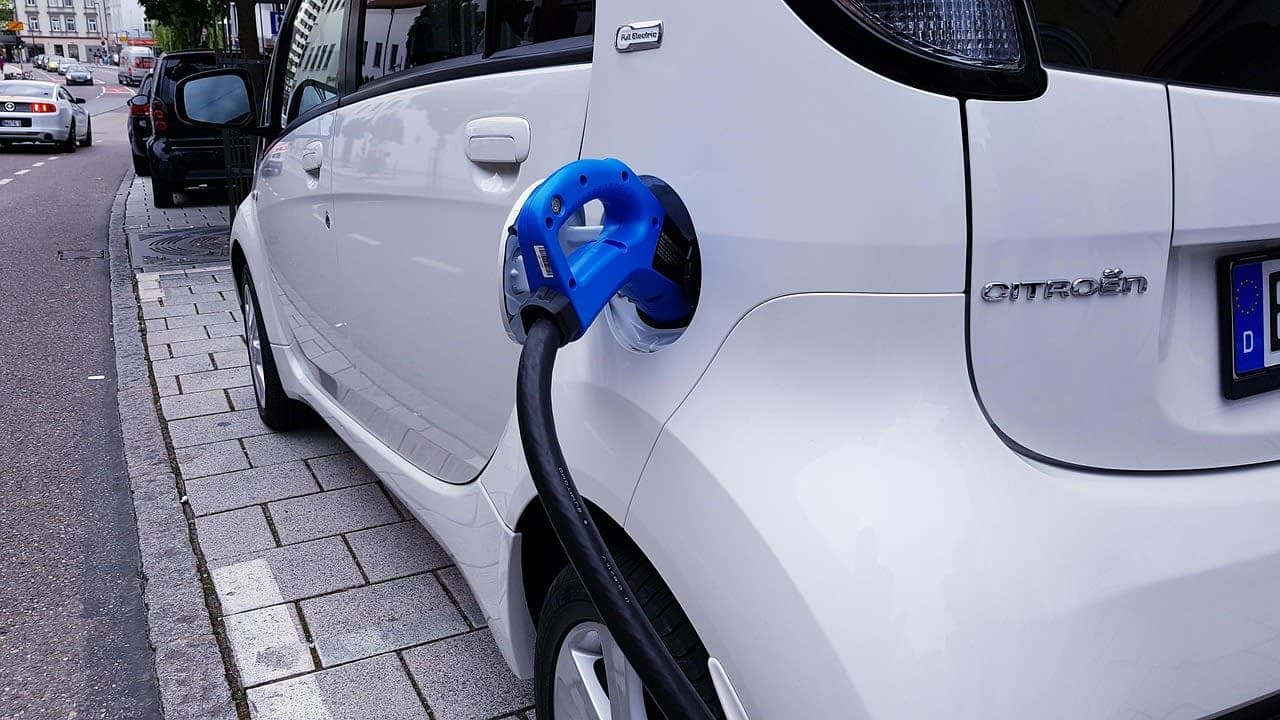 السيارات الكهربائية أصبحت خياراً حقيقياً لمن يحسبون تكلفة التنقل اليومي. family charging electric car at public charger station Germany residential street