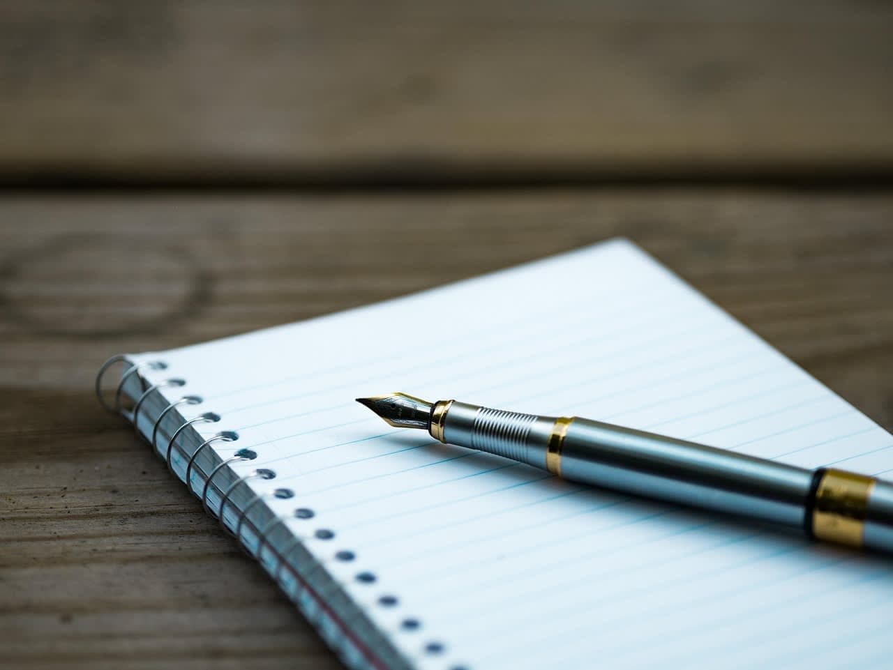 تدوين التاريخ والوقت والرابط مع كل لقطة شاشة يجعل الدليل قابلاً للاستخدام في المحكمة. hand writing notes on paper notebook, close-up, neutral desk