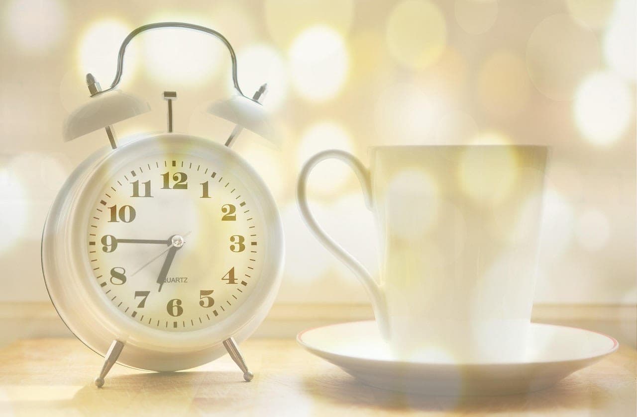 Zwei Wecker auf unterschiedlichen Geräten: der einfachste Schutz vor Verspätung am Montag two alarm clocks on bedside table morning light